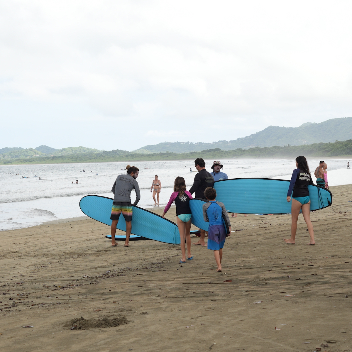 A family holding surfboards near the sea in Costa Rica. 