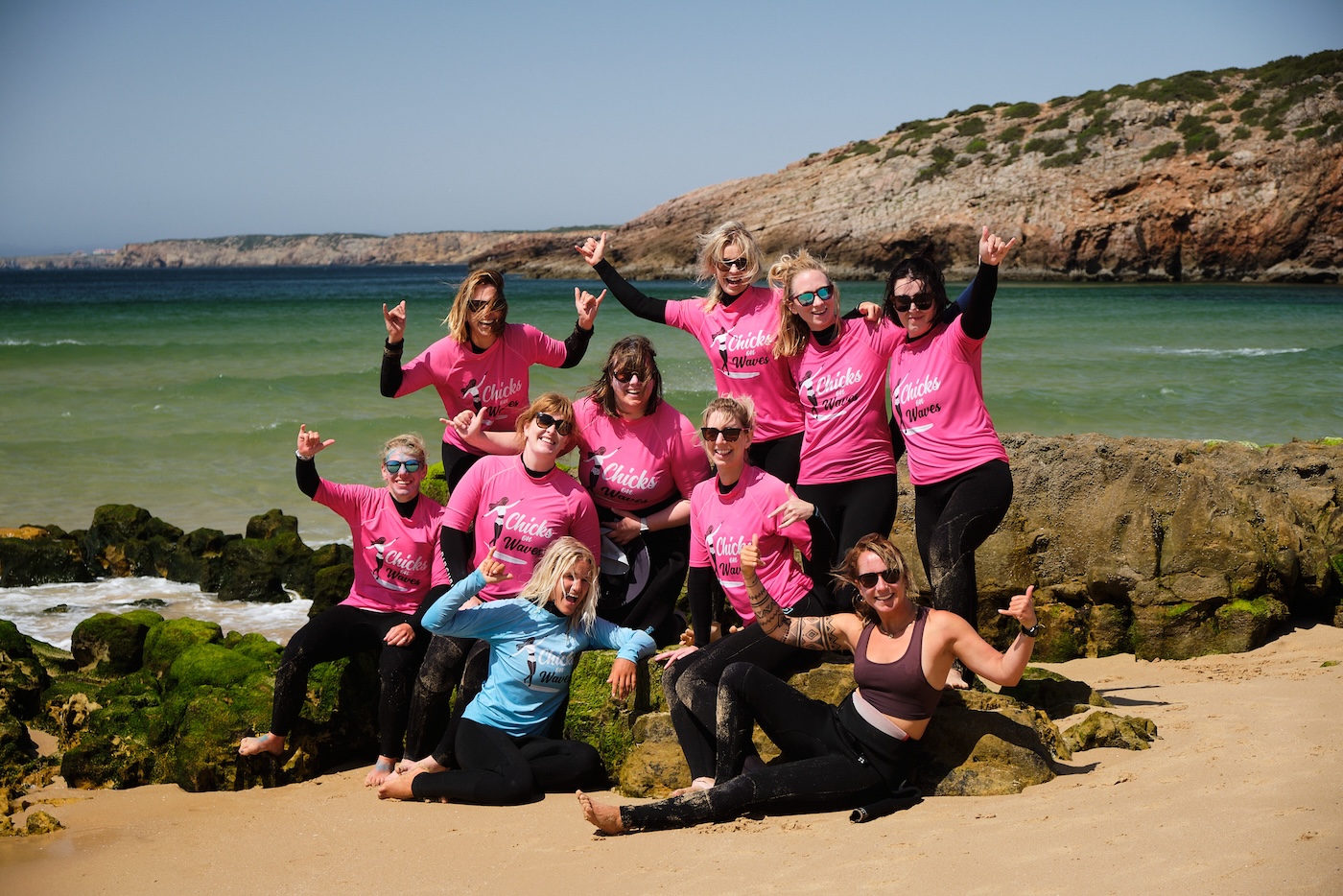 A group about to surf with Chicks on Waves A group on a female founded spaces surfing retreat. All waving at the camera