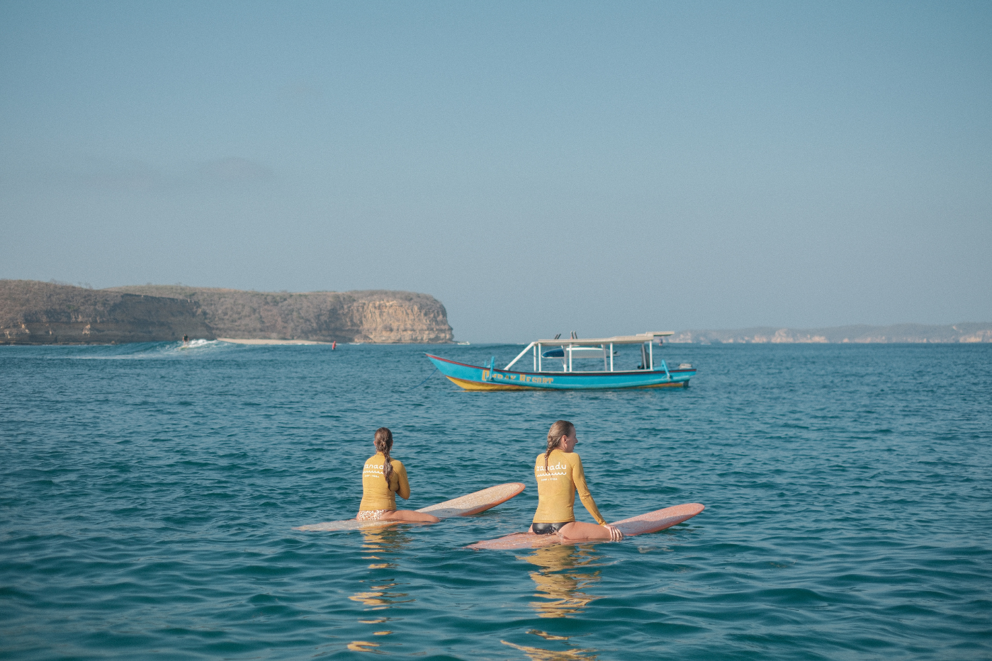 two girls sat on their surfboards waiting for a good wave at Xanadu Surf & Yoga.