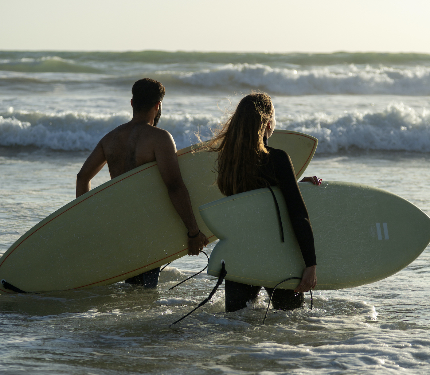 Two people walking out to surf at Paradis Plage