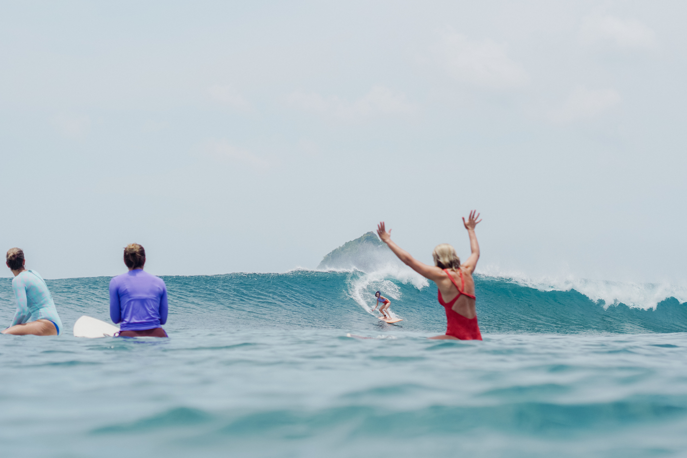 A girl surfing a wave at Xanadu, with other women in the foreground cheering her on