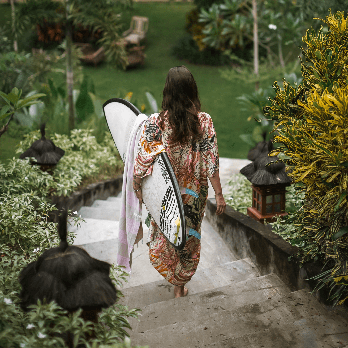Walking down the steps with a surfboard at Pelan Pelan