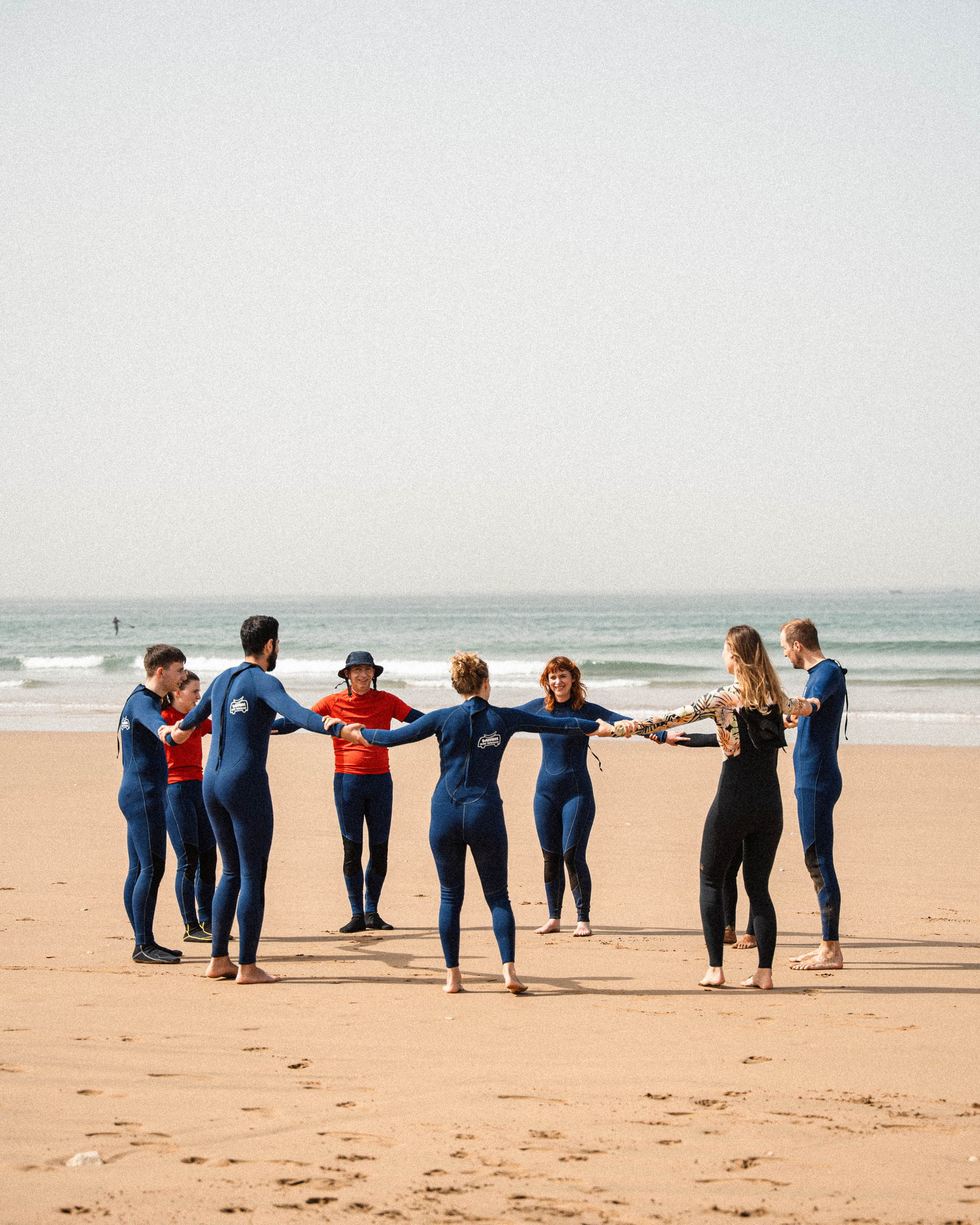 Surf group warming up in a circle on the beach before a lesson