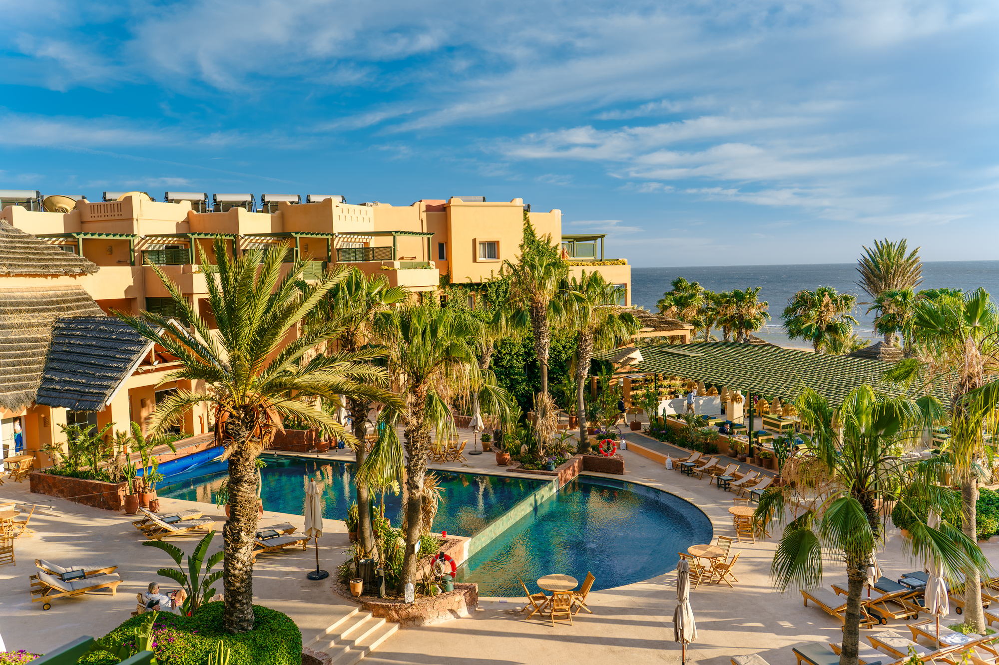 The pool, palms and ocean-facing rooms at Paradis Plage surf and yoga resort on the Atlantic coast of Morocco