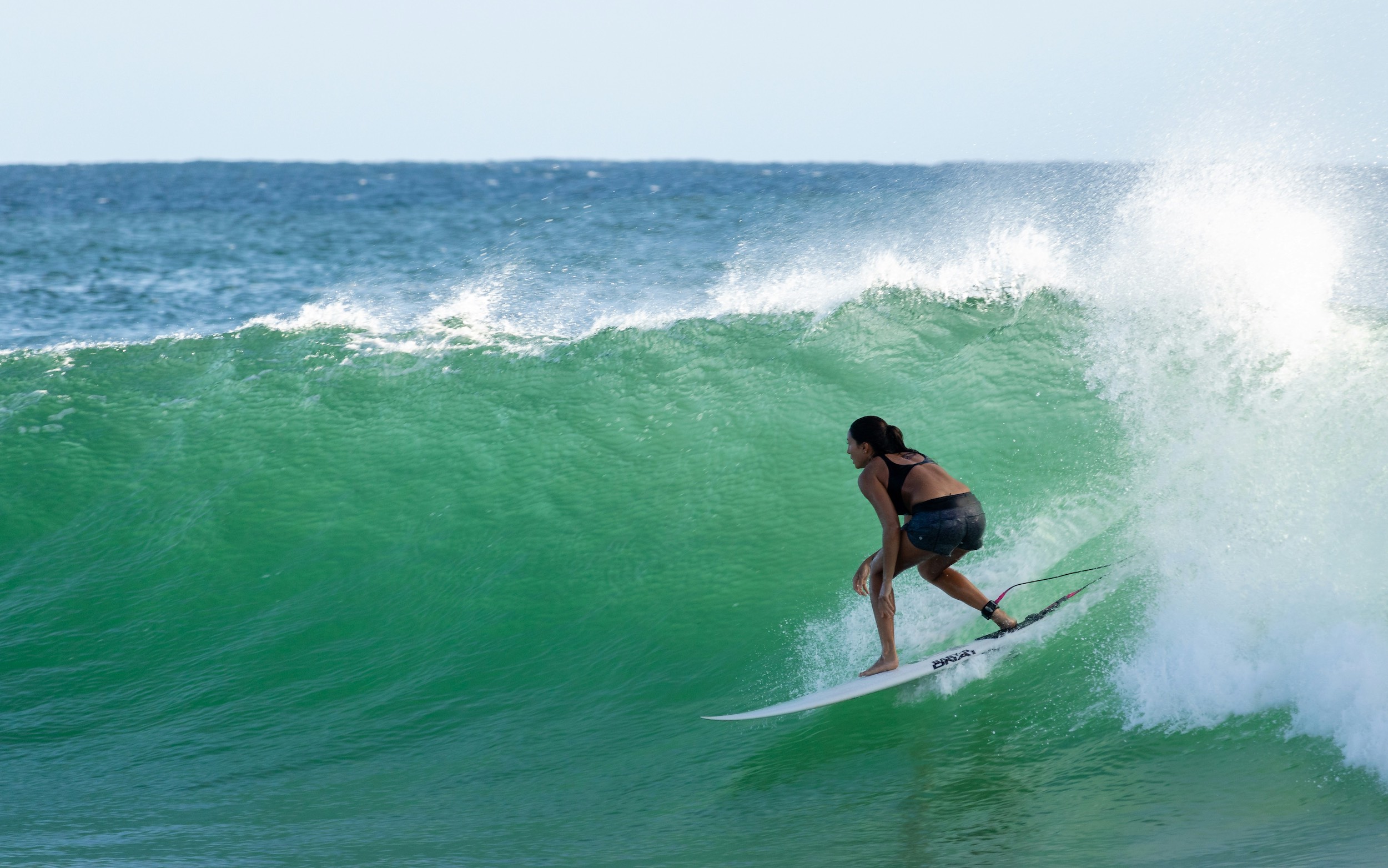 Surfer girl walking down to the ocean holding her surfboard