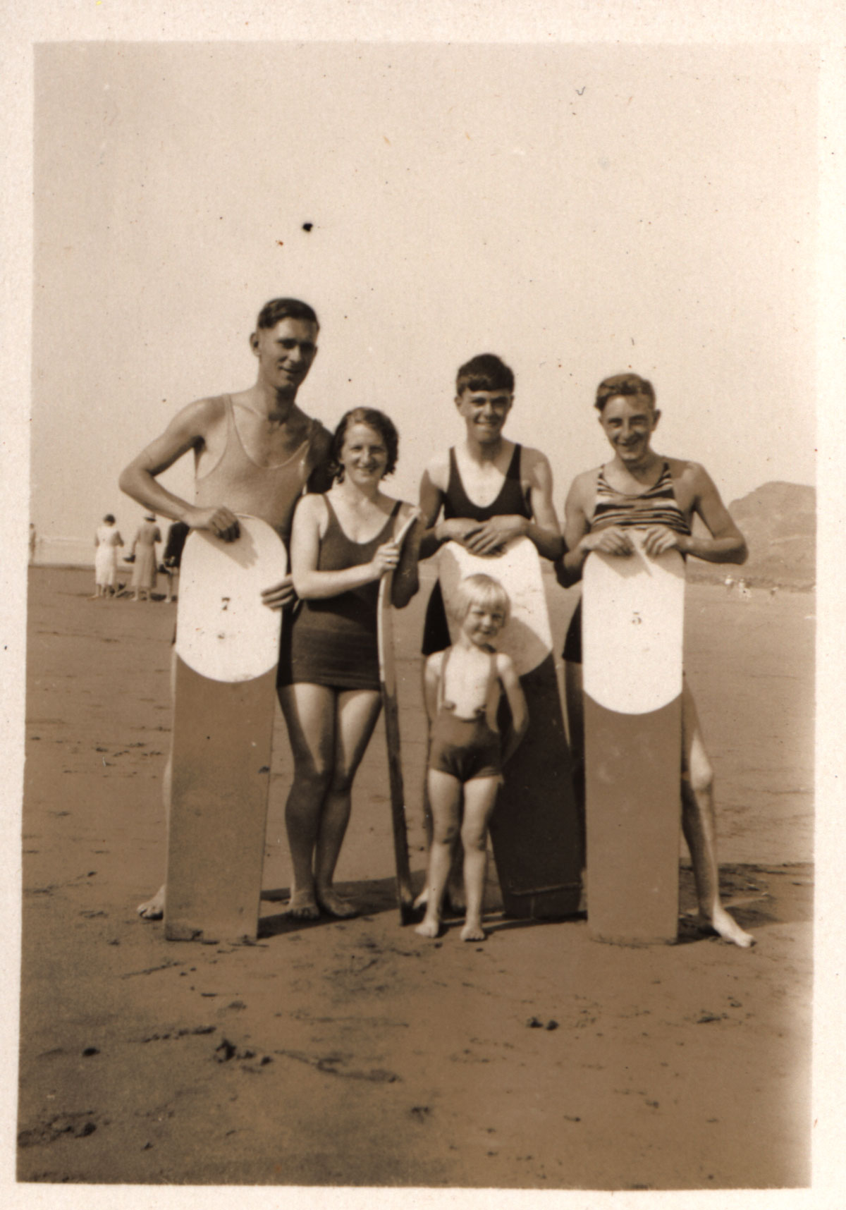 A woman and men holding wooden bellyboards on the beach at Bude in 1932